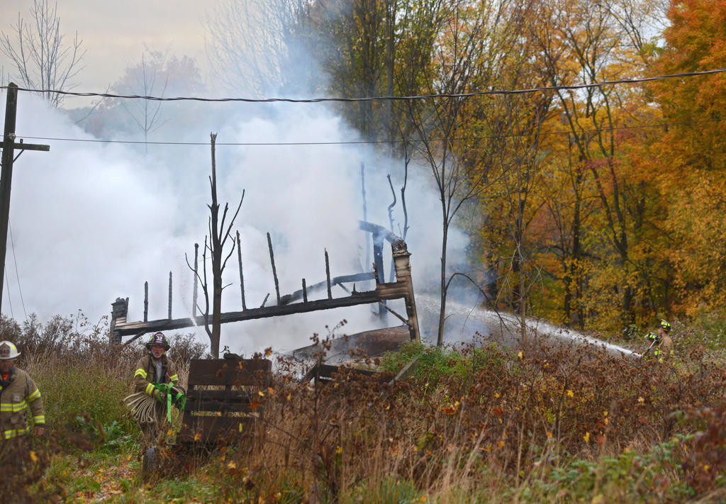 FARMHOUSE DESTROYED — Volunteers blast water on the remaining debris from an old, vacant farmhouse on Wynn Road in Trenton Friday morning.
 (Sentinel photo by John Clifford)