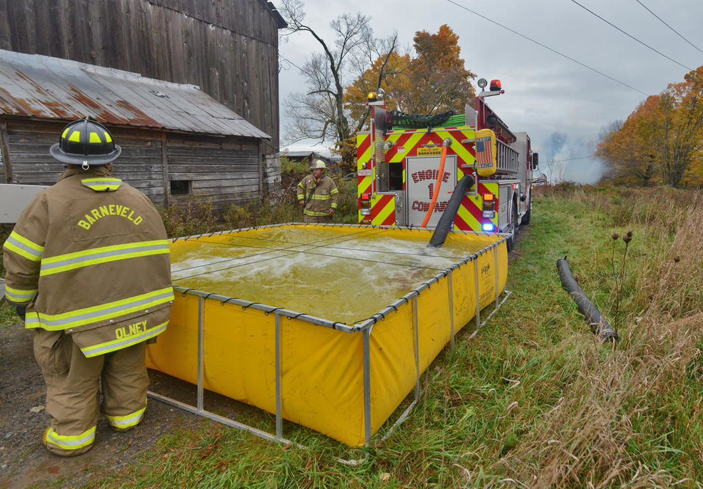FILL SITE — Volunteers man the portable pond outside the farmhouse fire on Wynn Road in Trenton Friday morning. The water gathered here feeds the hoses when a hydrant isn’t available.
 (Sentinel photo by John Clifford)