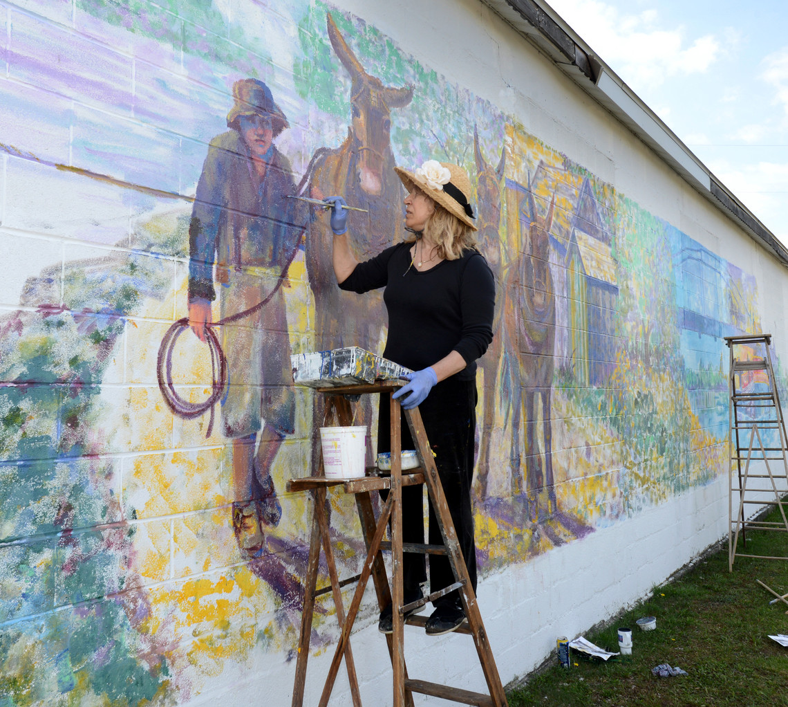 WORK IN PROGRESS — Artist Jane Taylor works on her latest mural in the Town of Verona.  The painting, which depicts parts of Higginsville, New London and Durhamville, was proposed by Town Historian Sheila Hoffman to celebrate the town’s rich heritage.
 (Sentinel photo by John Clifford)