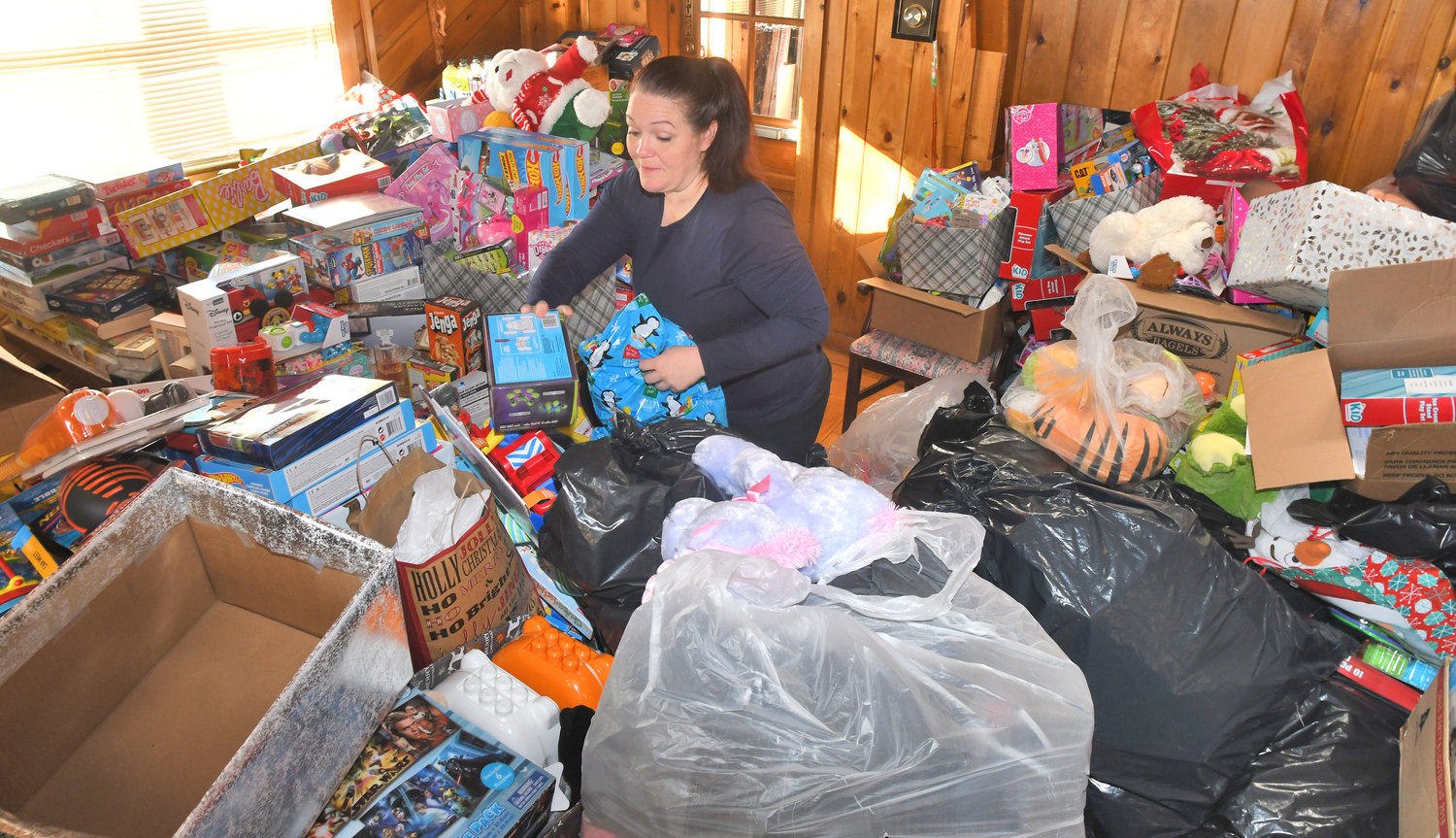 WRAPPING UP — Rescue Mission administrative assistant Destiny Branfalt stacks toys that will benefit needy families, including some 970 children, on Christmas day. The mission is still accepting toy and food donations to help brighten the holidays. See story, page 2.