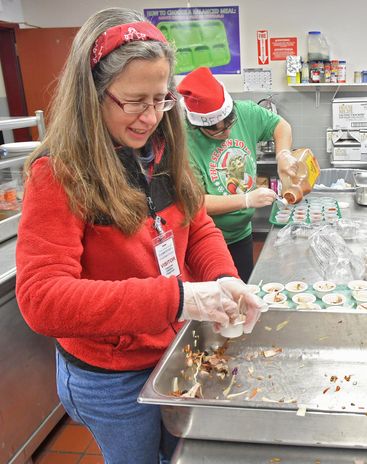 DISHING IT OUT — Clinton Elementary School parent volunteer Sarah McCullough dishes out Asian Cabbage Slaw into little cups for children to try during their lunch on Dec. 18 as part of the Harvest of the Month program.