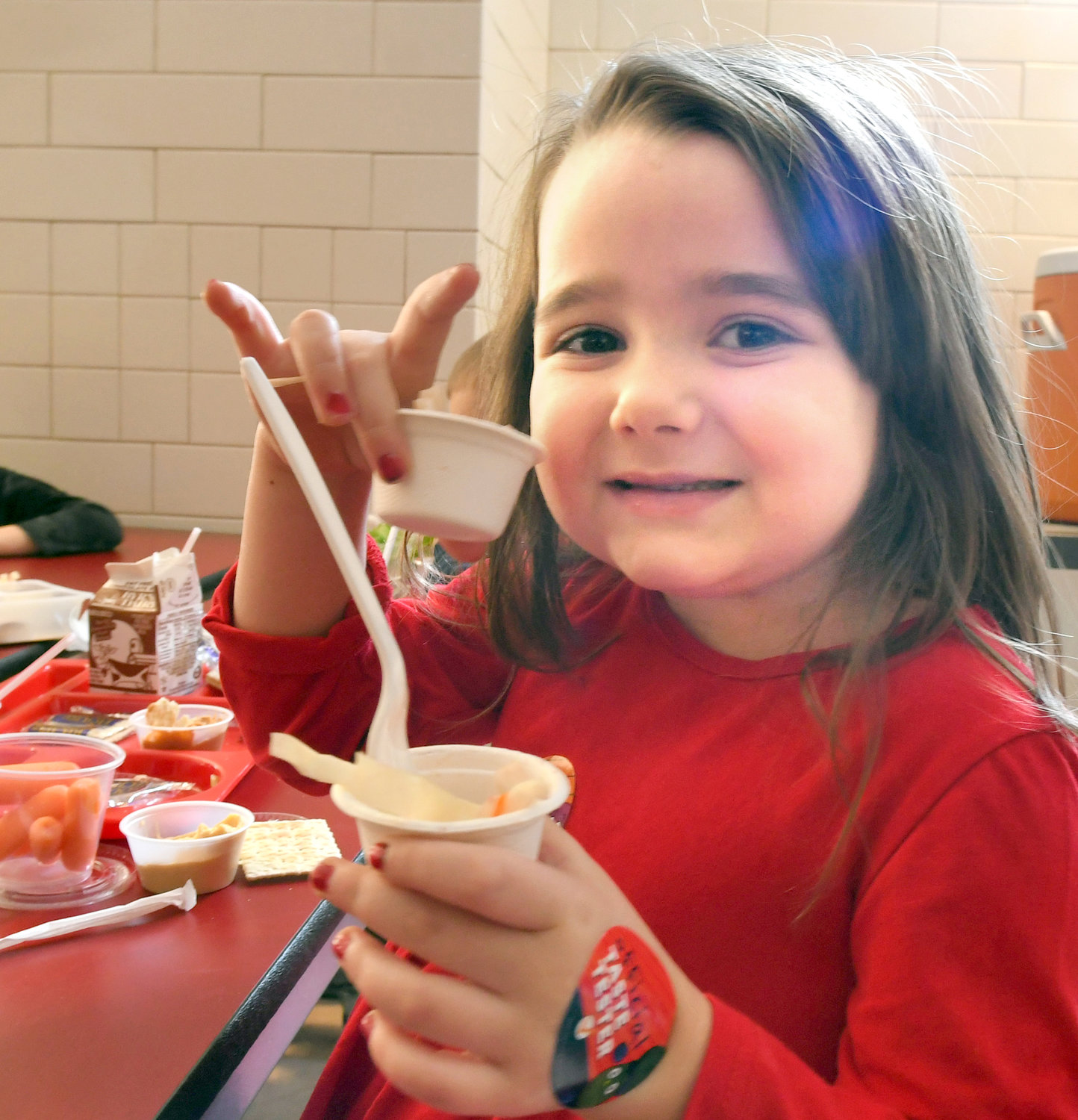 THIS IS GOOD — Clinton Elementary School kindergartener Alexandra Blum holds up the delicious Asian Cabbage Slaw that she tried during lunch on Dec. 18 as part of the Harvest of the Month program that’s part of the Farm to School initiative.