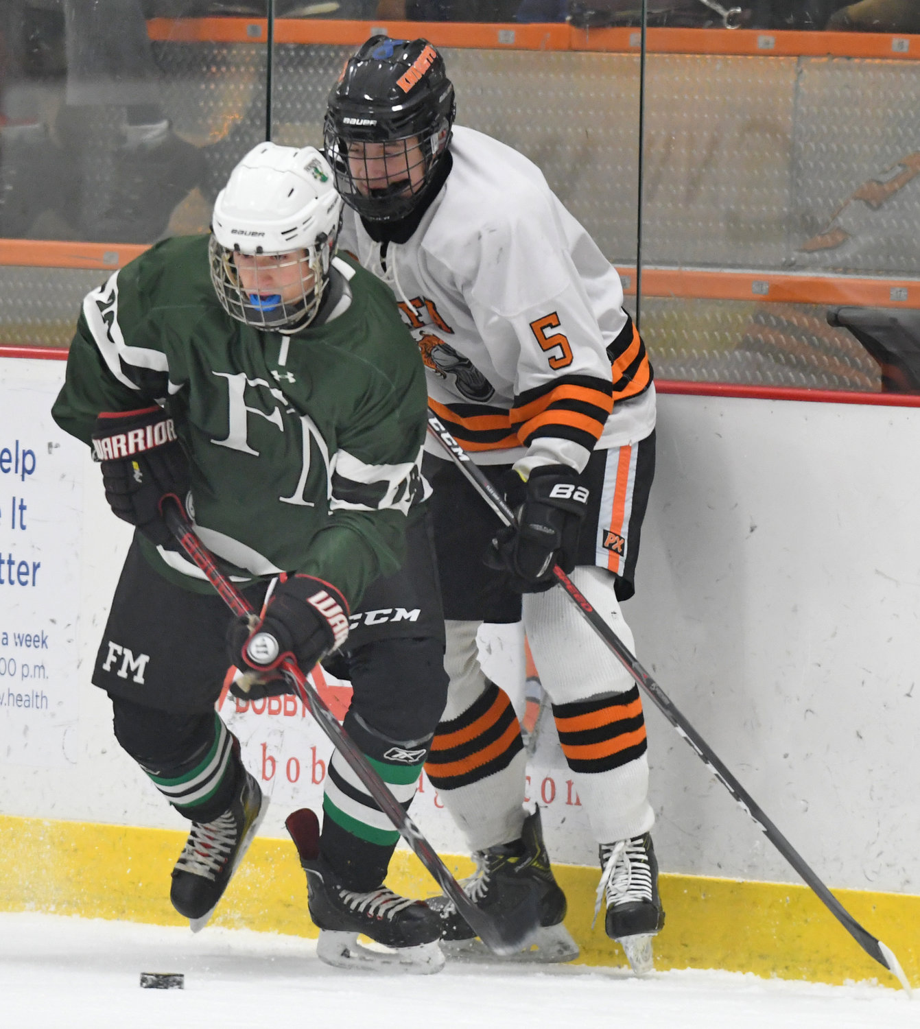 LOOKING TO CONTROL THE PUCK — Joey Gulla of RFA, right, battles with F-M’s Colin Debejian along the boards in the first period of Tuesday’s game at Kennedy Arena. The Hornets beat the Black Knights, 2-1.
