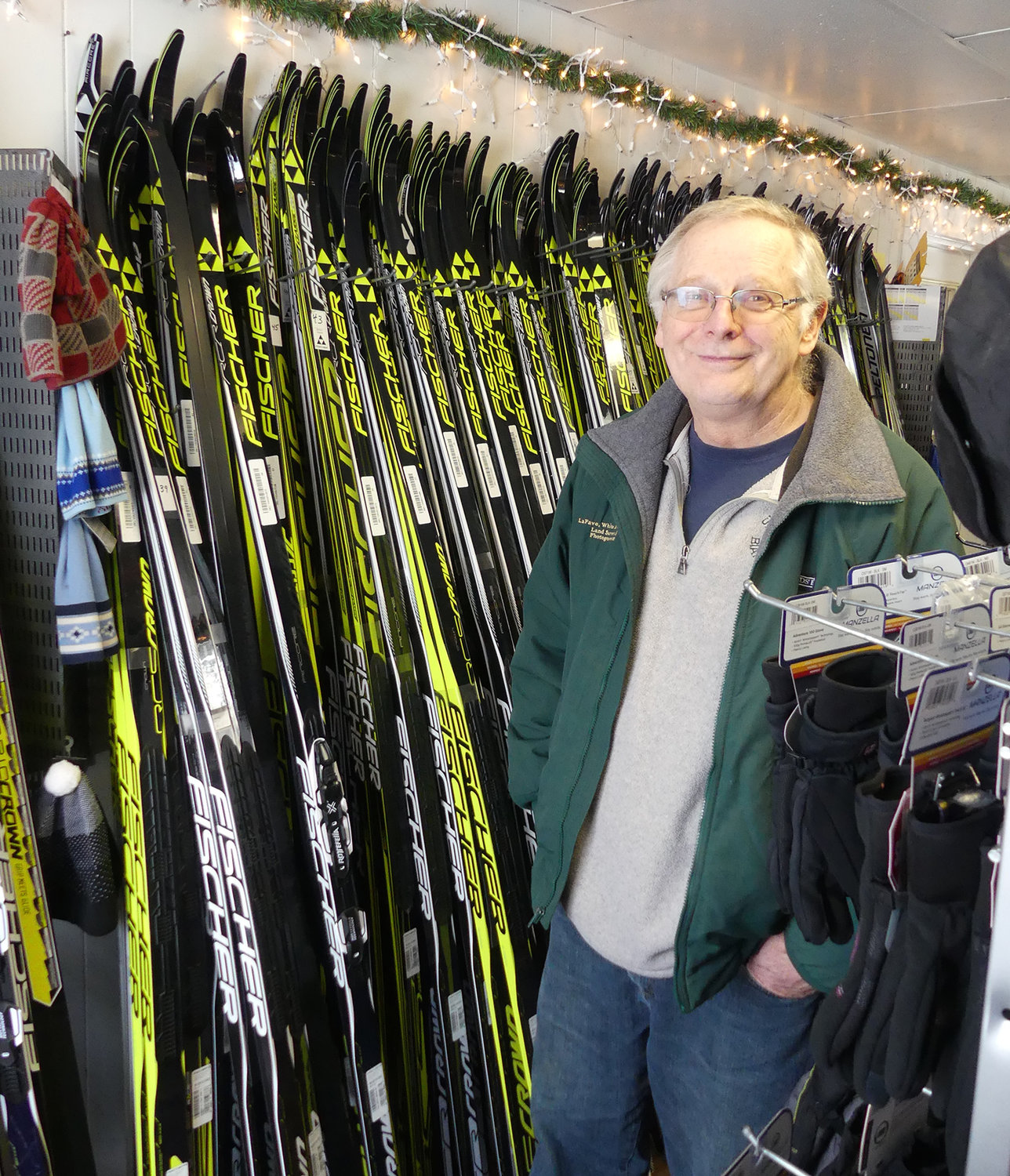 SKI CENTER — Hugh Quinn poses by skis for sale in the retail shop at Osceola-Tug Hill Cross Country Ski Center. The shop is part of the business that is for sale as Quinn and his wife, Anna, hope to leave it in new hands and retire by the end of next ski season.