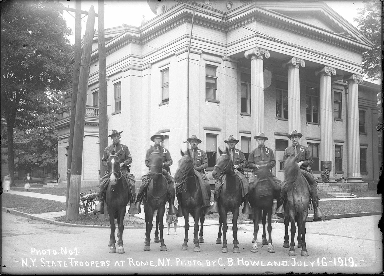 HERE COME THE TROOPERS — New York state troopers, on horseback, in front of the Rome Court House. The troopers helped restore peace after a violent strike in the city in 1919. They slept at the Court House, and kept their horses and cars in the city jail yard.