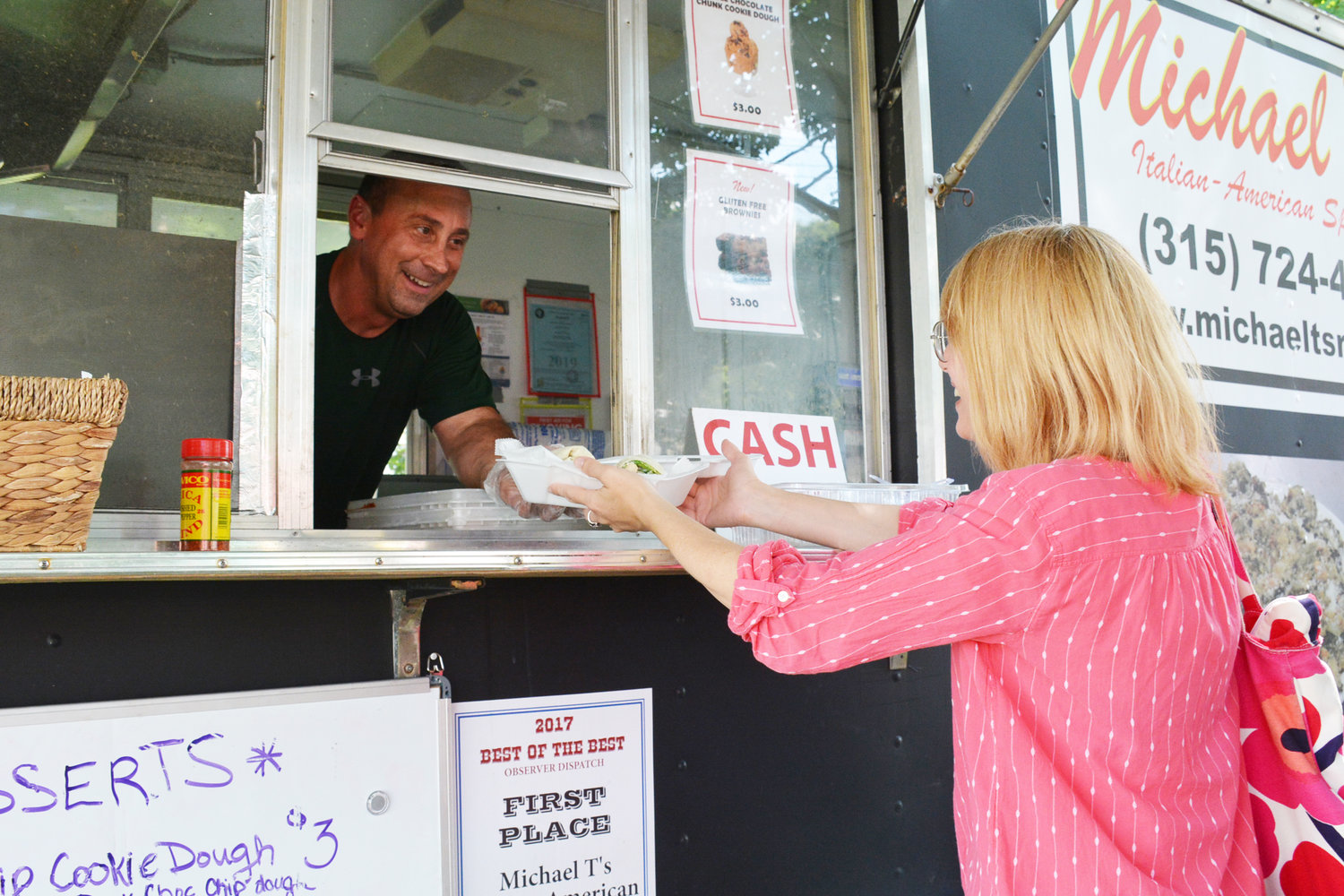 GREENS TO GO — Michael Trunfio, owner of Michael T’s food truck hands customer Nicolle Child an order at the Farmer’s Market on the Clinton Green, Thursday, Aug. 8. The Clinton resident has been operating the food truck in the village market for the past three years, but said this is his busiest year to date.