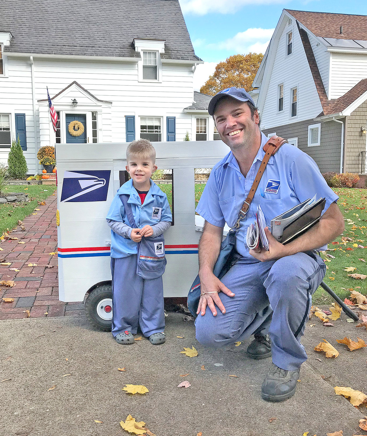 BUDDIES — Peter Corigliano IV wants to be a mailman when he grows up, which became the inspiration for his Halloween costume. Here, along with his own mail delivery truck, Peter is pictured with his buddy, professional postal worker Andy Wendt, who delivers mail in Peter’s neighborhood. (Photo submitted)