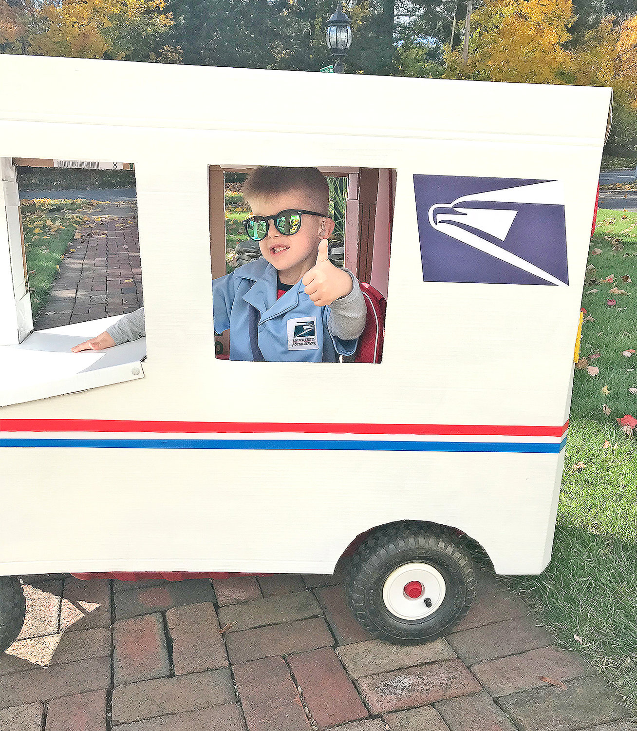 COOL RIDE — Peter Corigliano IV gives a thumbs up of approval inside his homemade U.S. Postal Service mail truck, designed and constructed by his grandmother, Carlene Corigliano.