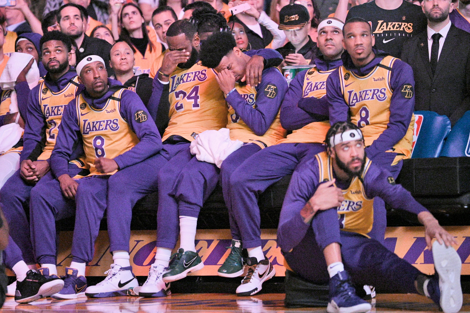 EMOTIONAL LAKERS — Los Angeles Lakers’ LeBron James, center, and Quinn Cook wipe their faces while watching a video tribute to Kobe Bryant, before the Lakers’ NBA game against the Portland Trail Blazers in Los Angeles on Friday night.