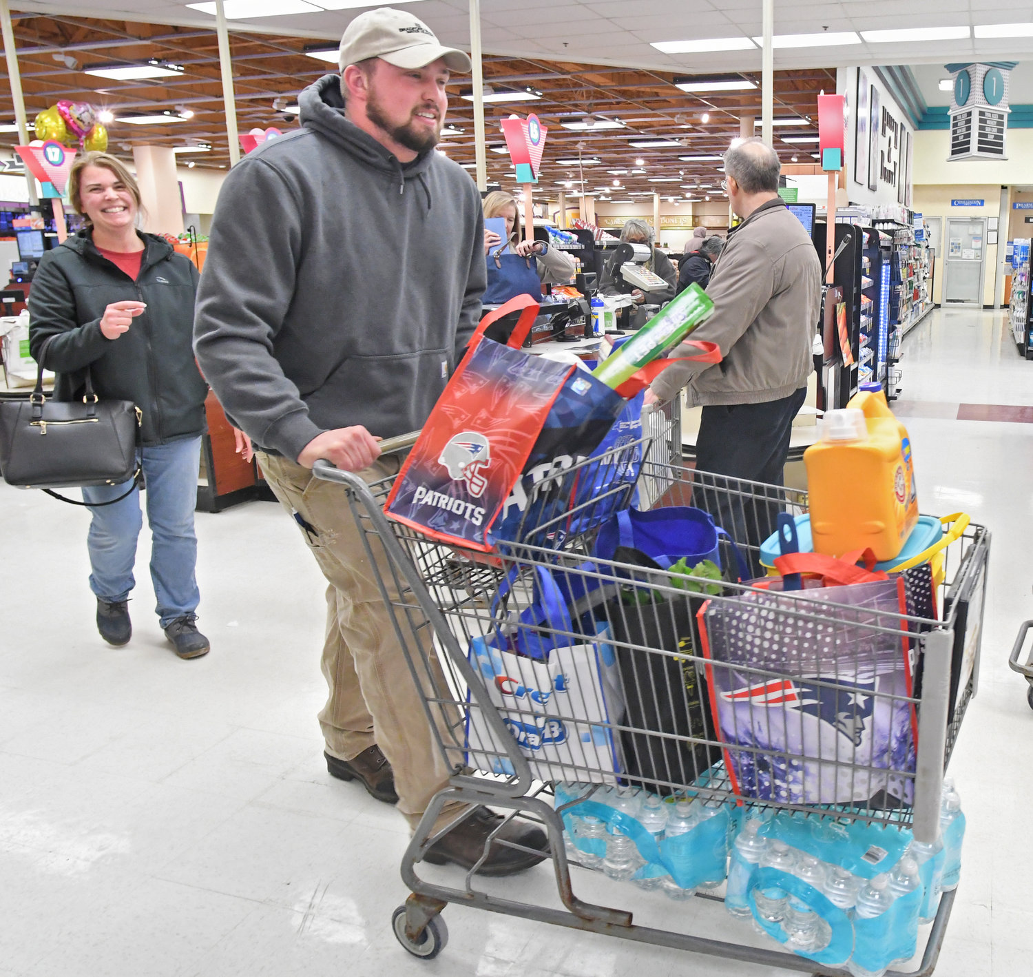 BAGGED — Ed Bentley, followed by his mother Debbie Bentley, carts away groceries that he bagged up in reusable bags Friday afternoon at Price Chopper on Black River Boulevard in Rome. Most of the Bentleys’ bags are from other stores, but Price Chopper says the company’s re-usable bags start at 50 cents each.