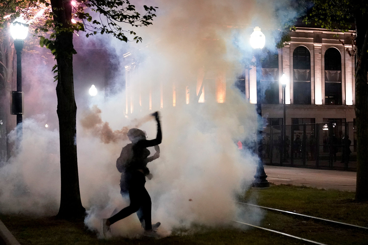 MORE VIOLENCE — A protester throws back a can of smoke toward law enforcement during clashes outside the Kenosha County Courthouse late Tuesday in Kenosha, Wis.