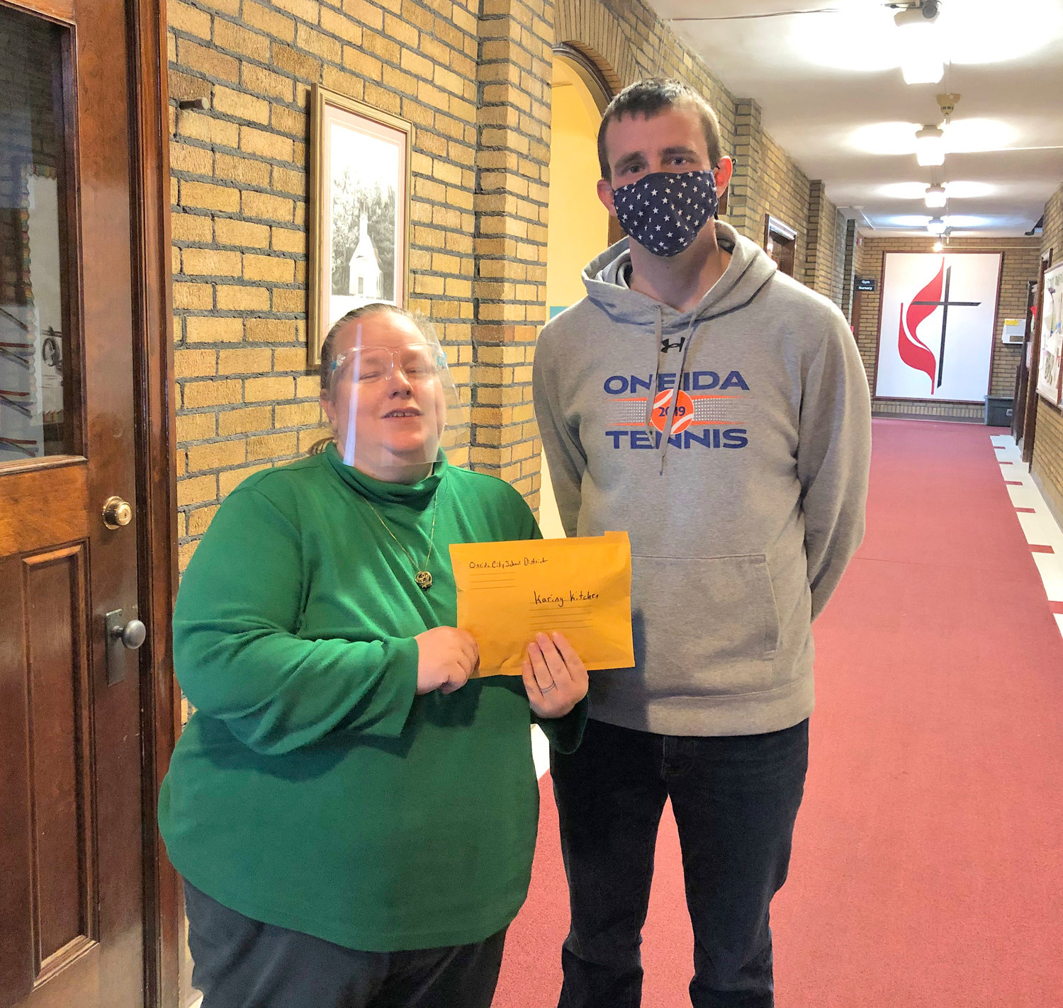 HOLIDAY HELPING — Oneida special education teacher and student council adviser Chris Meeker presents Karing Kitchen Coordinator Melissa King with monetary donations from the Oneida School District faculty totaling $1,916 after the traditional canned food drive was canceled amid COVID-19 concern.