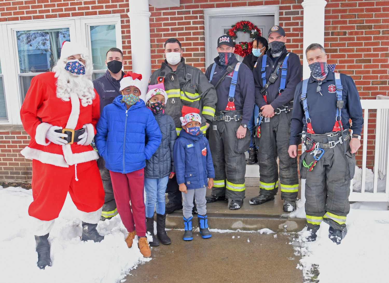 Rome FD firefighters with one of the four family of children that were given gifts by the RFD with funds donated by firemen Monday afternoon at Libery Gardens.