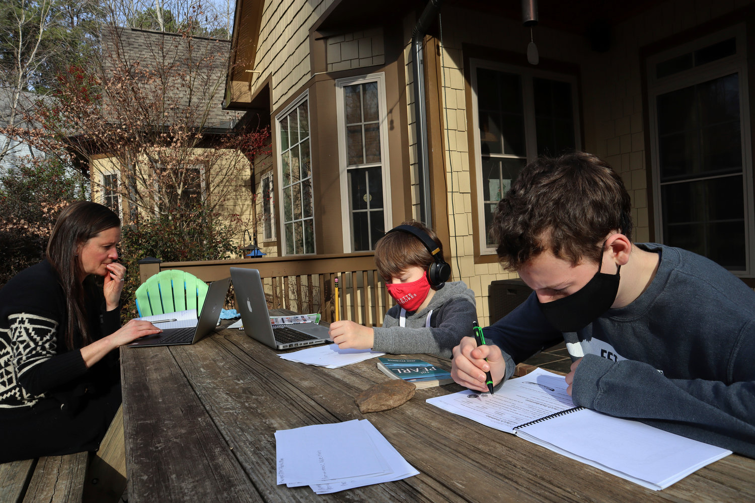 STUDY TIME — Angela Atkins works outside her home in Oxford, Miss., on Friday, Dec. 18, while her two sons, Jess and Billy, focus on schoolwork. Atkins is home schooling her children for the first time this year while juggling her job in the development office at the University of Mississippi. Atkins said her job has allowed her to work from home while managing her children’s education.