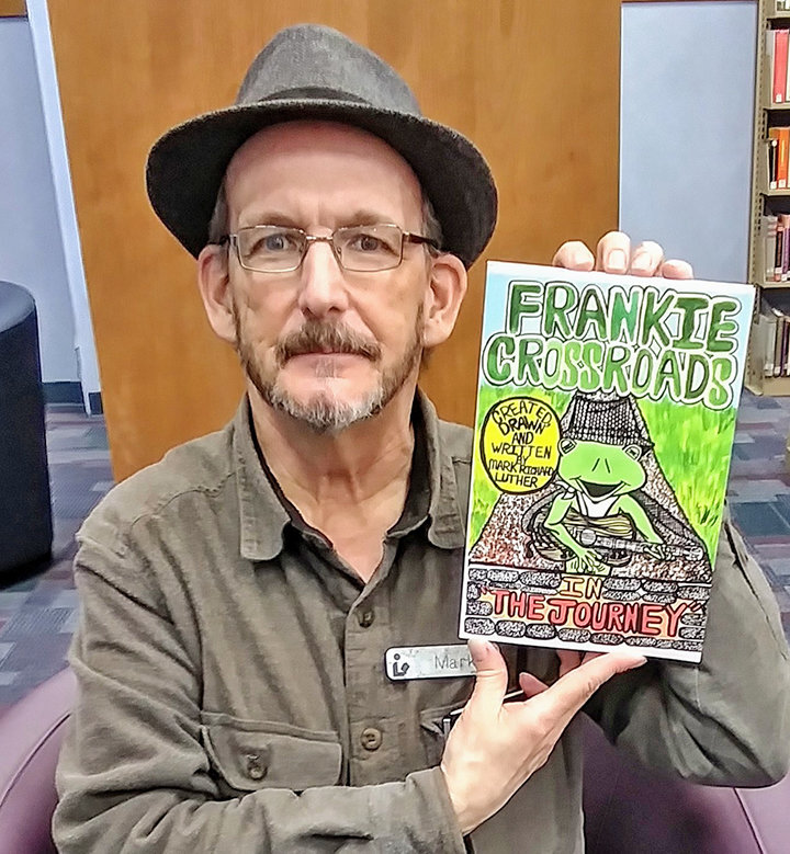 A LOVE TO DRAW — Herkimer writer and cartoonist Mark Luther holds up a copy of his first published graphic novel “Frankie Crossroads — The Journey.”
