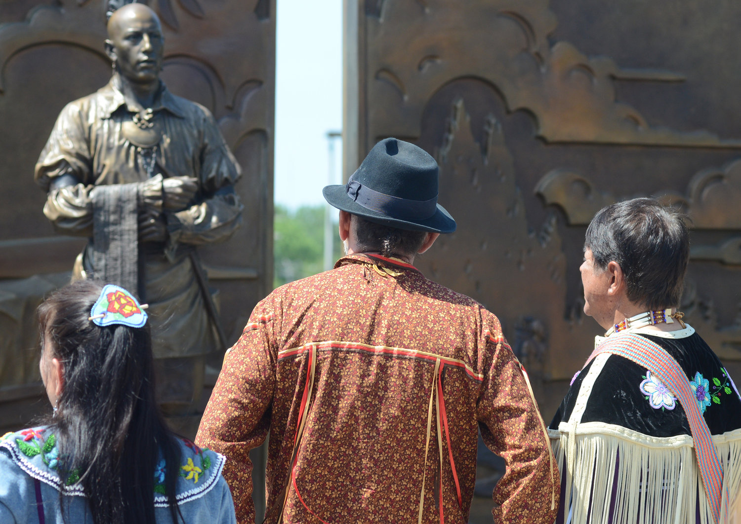 HONORING THEIR ANCESTORS — Brian Patterson, center, representative of the Bear Clan of the Oneida Nation Council, along with Sheri Belgen, left, Wolf Clan, and Oneida Nation Representative Ray Halbritter, right, look over the artwork after the official unveiling of the new Oneida monument on West Dominick Street Tuesday.