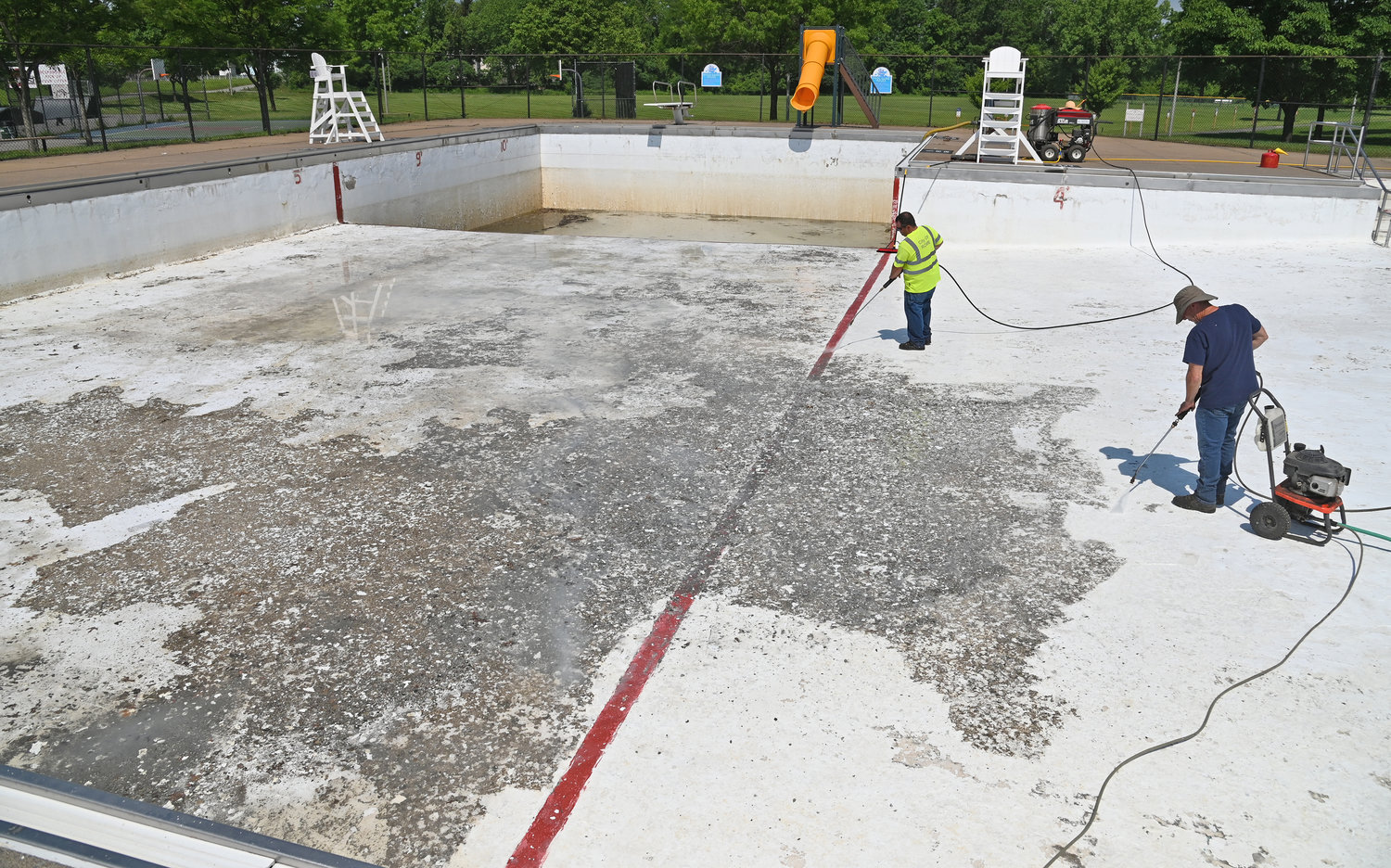 GETTING READY FOR SUMMER — City Parks employees Lenny Costello and Dave Bruno pressure wash grime and old paint from the bottom of Tosti Pool at Pinti Field on Monday. Crews will paint the pool before filling it and re-opening for the start of the swimming season in July. The Michael Uvanni Municipal Pool on West Embargo Street and the Guyer Field pool on Laurel Street will also open —but City Parks &amp; Recreation Director James Korpela said the city is only opening three of its five pools this summer due to a lack of lifeguards.  He said the city had to contract with the YMCA of the Greater Tri-Valley in order to have enough staff for the three pools to operate.  The department, he said, has plenty of chlorine to keep its pools clean this season after reports hit last month there may be a shortage of chlorine tablets this year due to a fire at a chemical plant in Louisiana. The good news for hot city residents is that it will cost less to swim this year as the city is  waiving its $1 admission fee for using the pools this year.