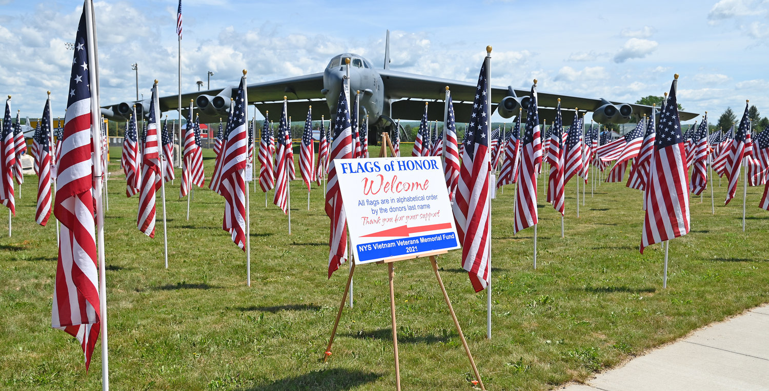 FLAGS OF HONOR — Some of the 500 flags stand in the foreground, behind a sign outlining the project, a fundraiser for the New York State Vietnam Veterans Memorial Fund, Inc., watched over by the static B-52 Bomber display on the Griffiss Business and Technology Park. All funds raised by the project — primarily through sponsorships of flags — will go to the fund.