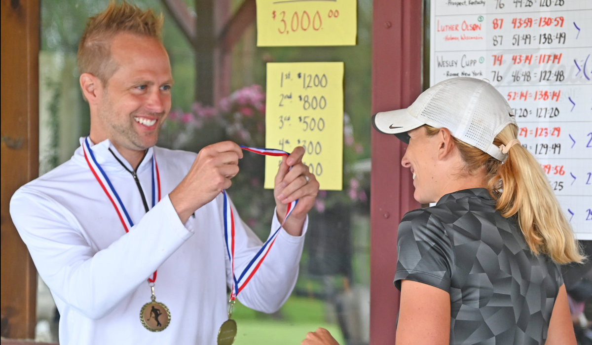 EARNING THE MEDAL — Rome’s Lauren Cupp receives her medal from husband Wes Cupp after finishing the Thirsty Owl New York Speedgolf Open Monday morning at Rome Country Club. The Cupps stole the show with Wes winning the Open Division and Lauren setting a new world record for women’s Speedgolf.