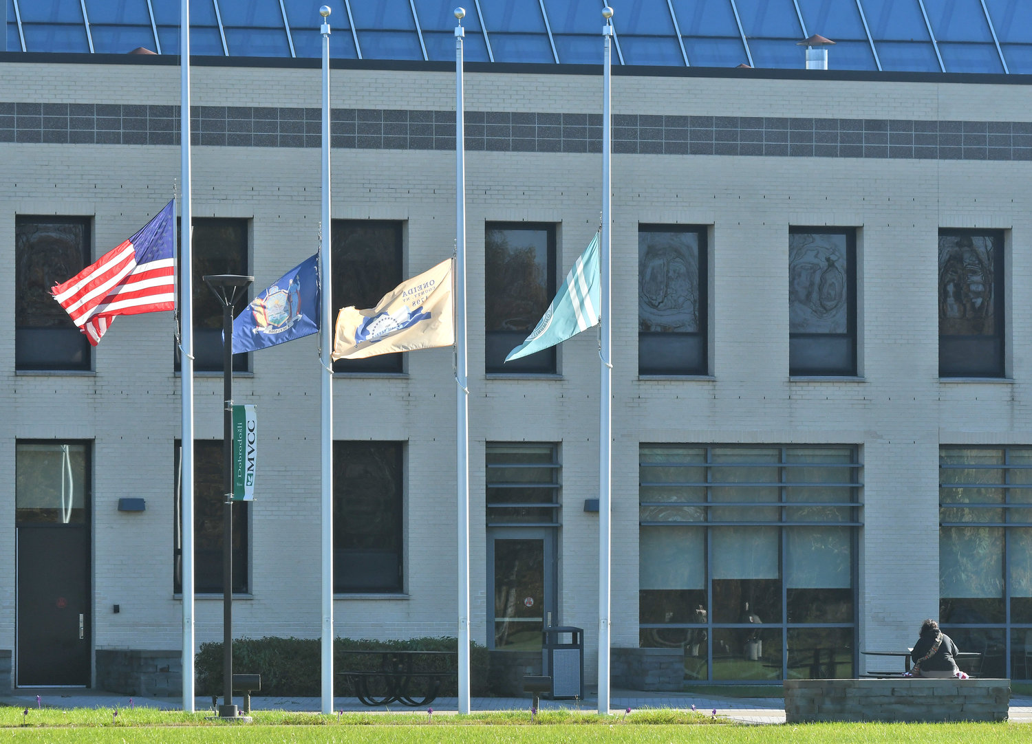 Flags at MVCC campus with a student sitting at a nearby table.