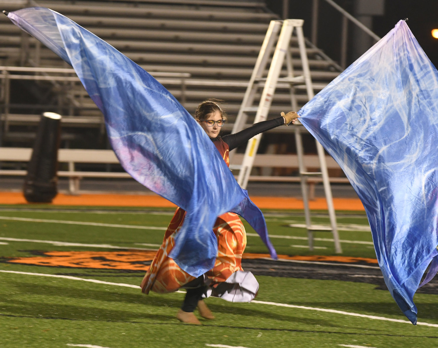 SHIMMERING — Color guard member Olivia Burch rhythmically waves a pair of brightly-colored flags.