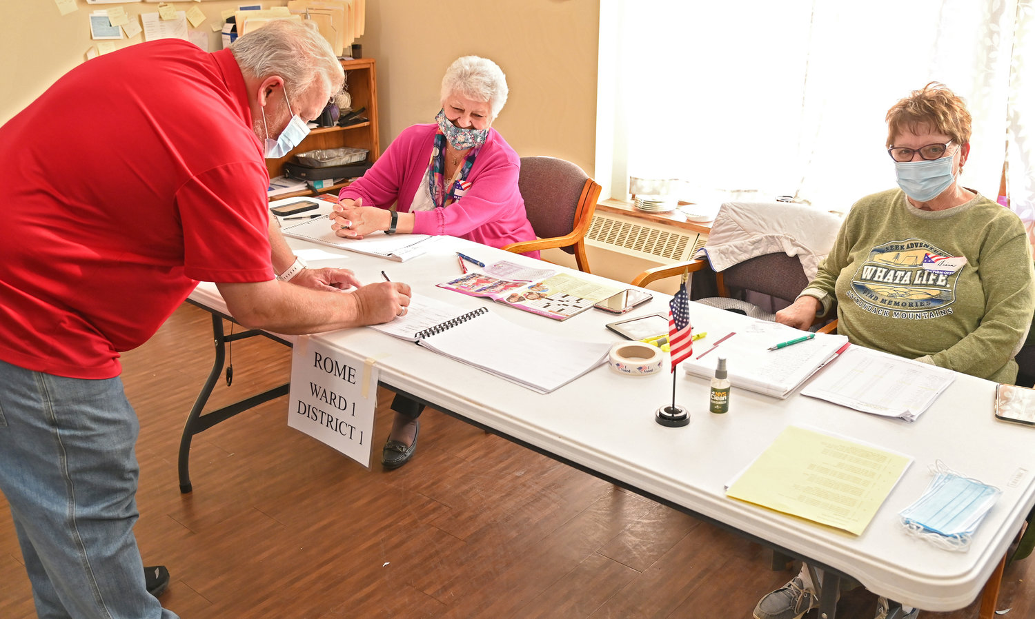 SIGNING IN — Voter Donald Narrow signs the book with voting inspectors Patricia Johnson and Diana Dargenio looking on in the city’s Ward 1 at the Copper City Community Connection, 305 E. Locust St., on Tuesday.
