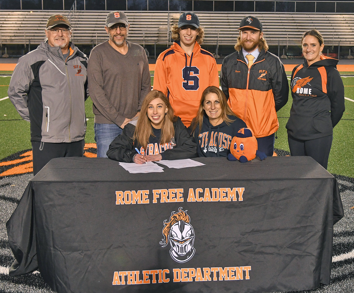 HEADED TO SYRACUSE — Emily Toth-Ratazzi signs her letter of intent to run cross country at Division I Syracuse University next year. The Rome Free Academy senior is joined by her mother, Shirley Toth. Standing with them are, from left: coach Brett Couchman, her father Paul Ratazzi, her brother Nicholas Toth-Ratazzi, coach Nick Jeror and coach Diane Benedict-Stevenson.