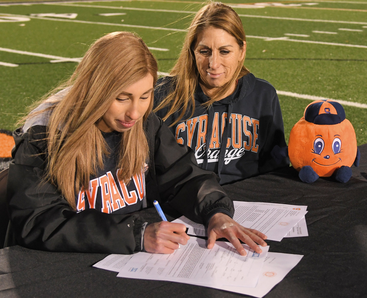READY TO RUN — Emily Toth-Ratazzi signs her letter of intent to run cross country next year at Syracuse University. The Rome Free Academy senior signs as her mother, Shirley Toth, looks on at RFA Stadium Monday.