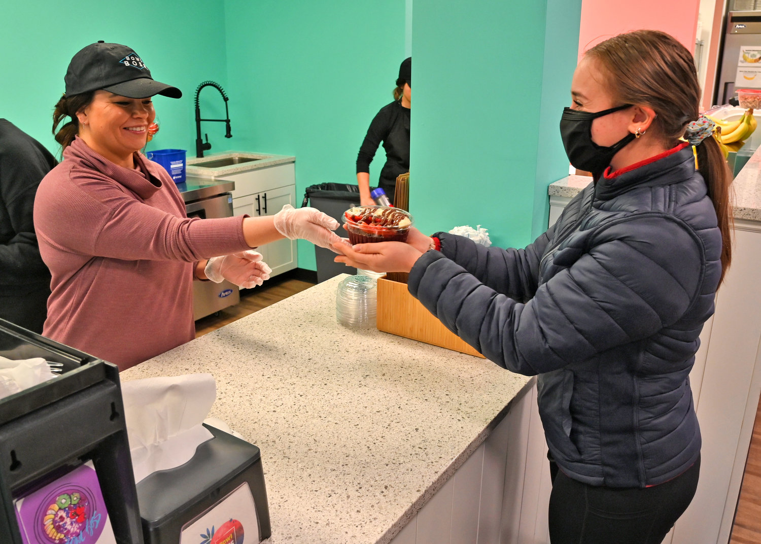 ENJOY! — Bowl Boss Owner Stacey Catalano, left, hands customer Elizabeth Libertella her purchase of the Coco Cabana bowl during the store’s grand opening on Monday, Nov. 22. Bowl Boss features an array of fruity, healthy bowls, smoothies and other items.
