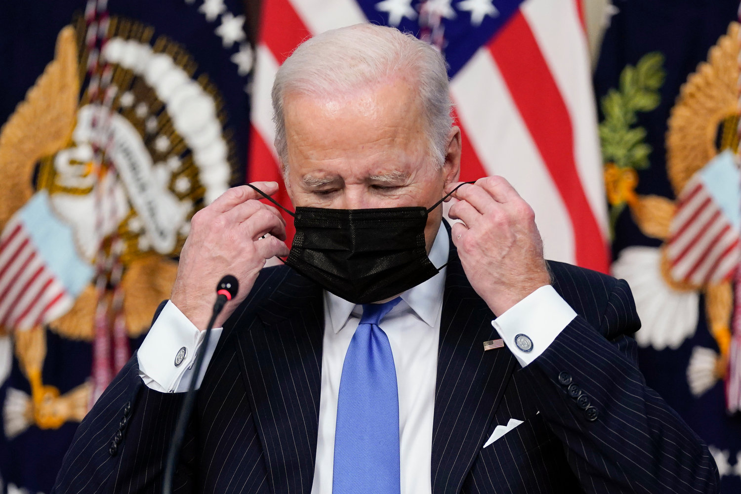 MASK TIME — President Joe Biden adjusts his face covering as he speaks during a meeting with business leaders about the holiday shopping season, in the library of the Eisenhower Executive Office Building on the White House campus Monday in Washington.