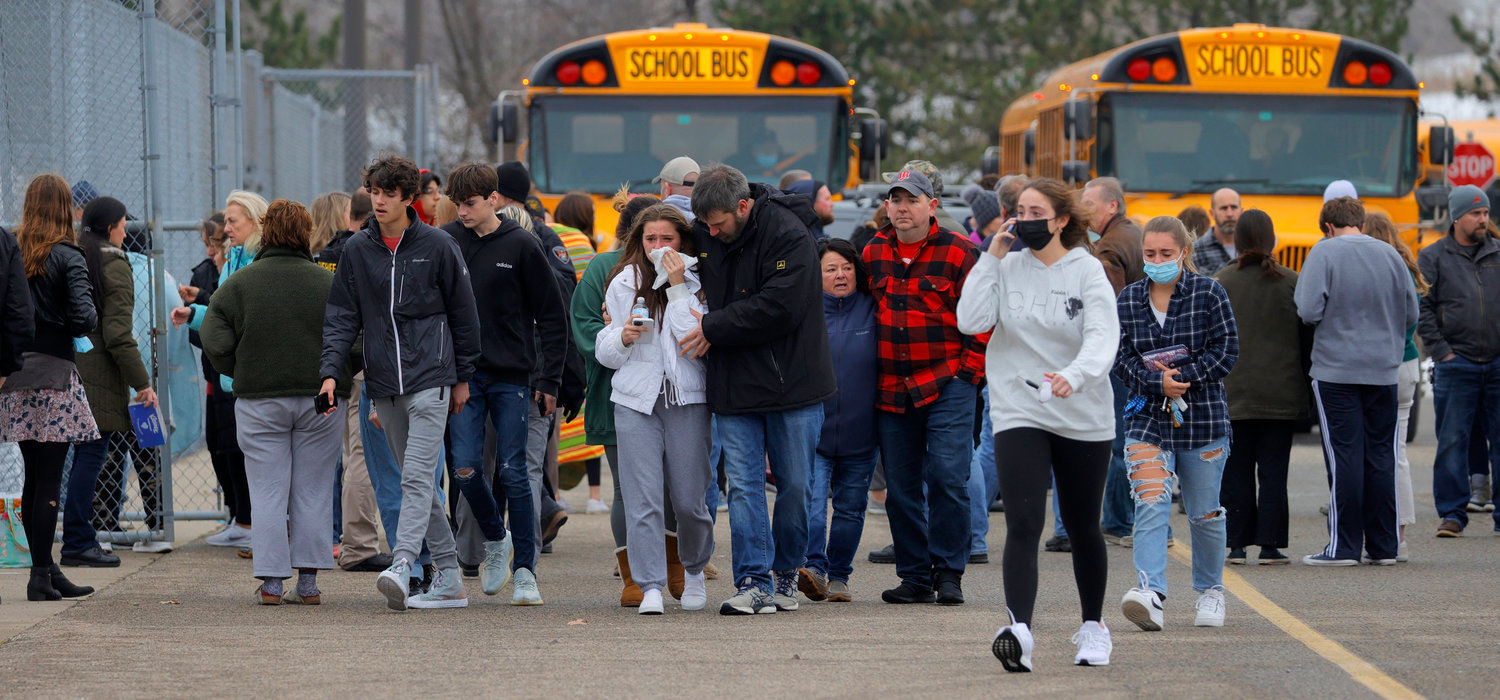 REUNITED — Parents walk away with their kids from the Meijer’s parking lot, where many students gathered following an active shooter situation at Oxford High School Tuesday in Oxford, Mich. Police took a suspected shooter into custody. At least three students were killed.