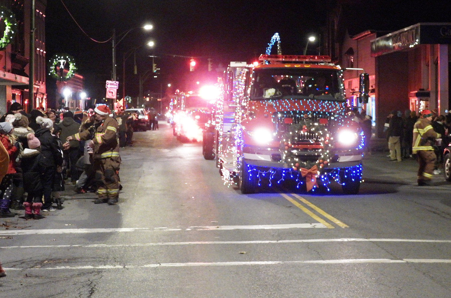 CHRISTMAS ON MAIN STREET — The first-ever Oneida Parade of Lights makes its way down Main Street. Pictured is the Munnsville Fire Department and their festive fire truck, handing out candy to good little boys and girls. For more photos of the Oneida Christmas Festival, visit the Rome Sentinel website.