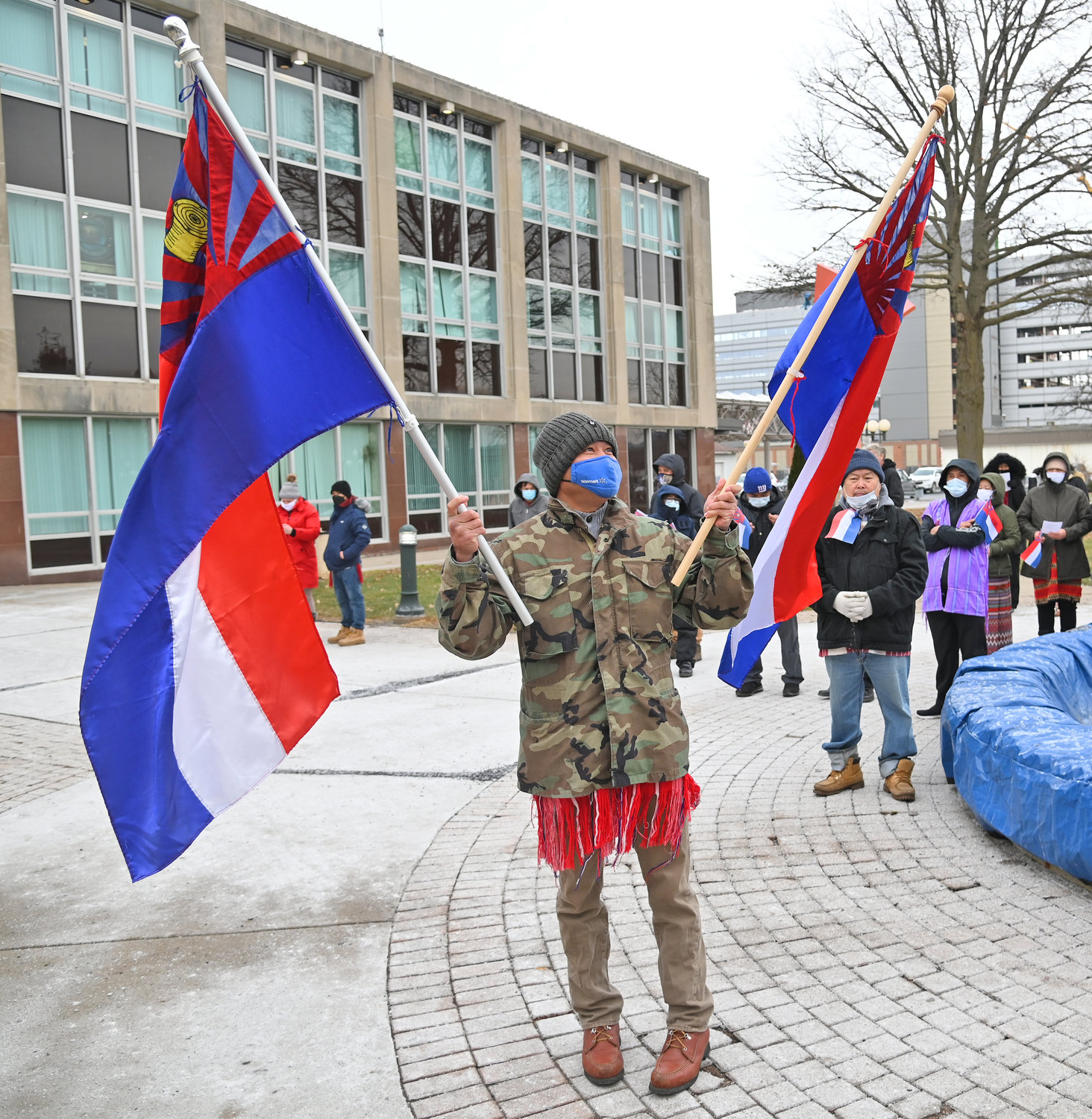 SHARING THE CULTURE — Bwe Htoo holds a pair of Karen Community Flags Wednesday at Utica City Hall prior to the flag raising ceremony.