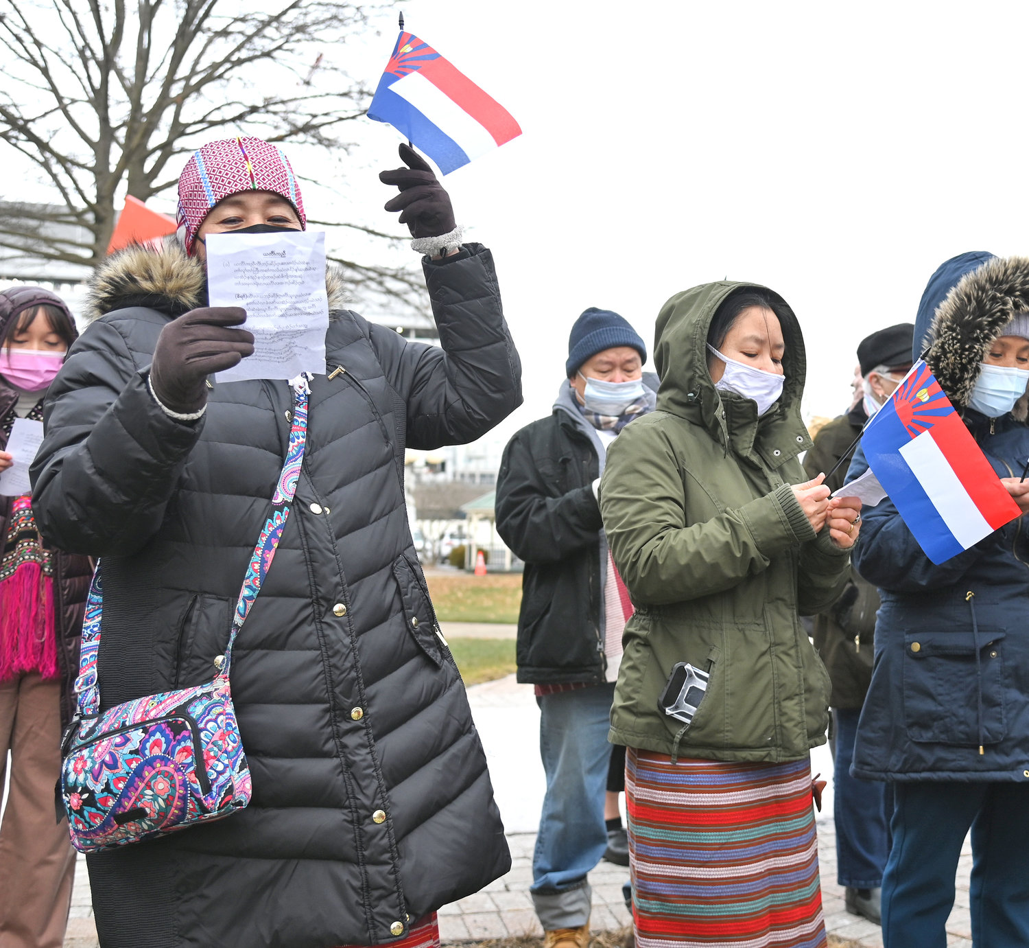 Sayway Htoo raises her flag while singing during the Karen Community Flag raising ceremony at Utica City Hall. Next to her, Lah Hser is also singing.
