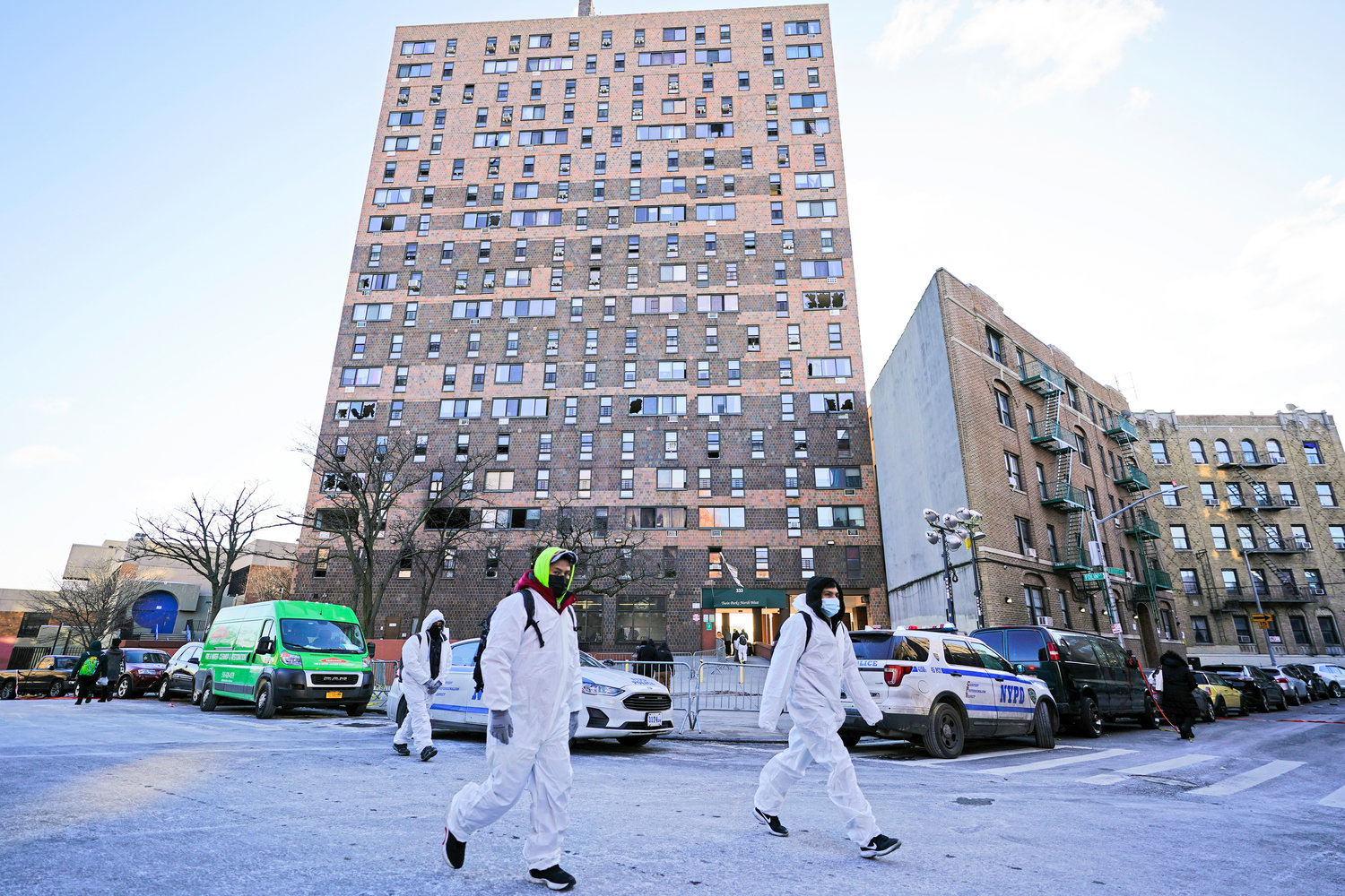 CLEANING UP — Workers in protective clothing walk from an apartment building which suffered the city’s deadliest fire in three decades, in the Bronx borough of New York, Tuesday, Jan. 11, 2022. A malfunctioning electric space heater apparently started the fire Sunday in the 19-story building in the Bronx, fire officials said.
