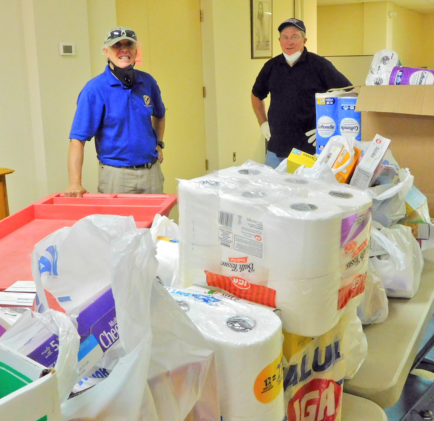 VOLUNTEER EFFORT — A pair of volunteer workers sort through food, paper goods and other supplies that were distributed to individuals and families in need in the Oneida area by the Karing Kitchen in this July 2020 file photo. The organization, which helps feed those in need in the area, is taking a one-week breather and will return to assist the hungry in the region.