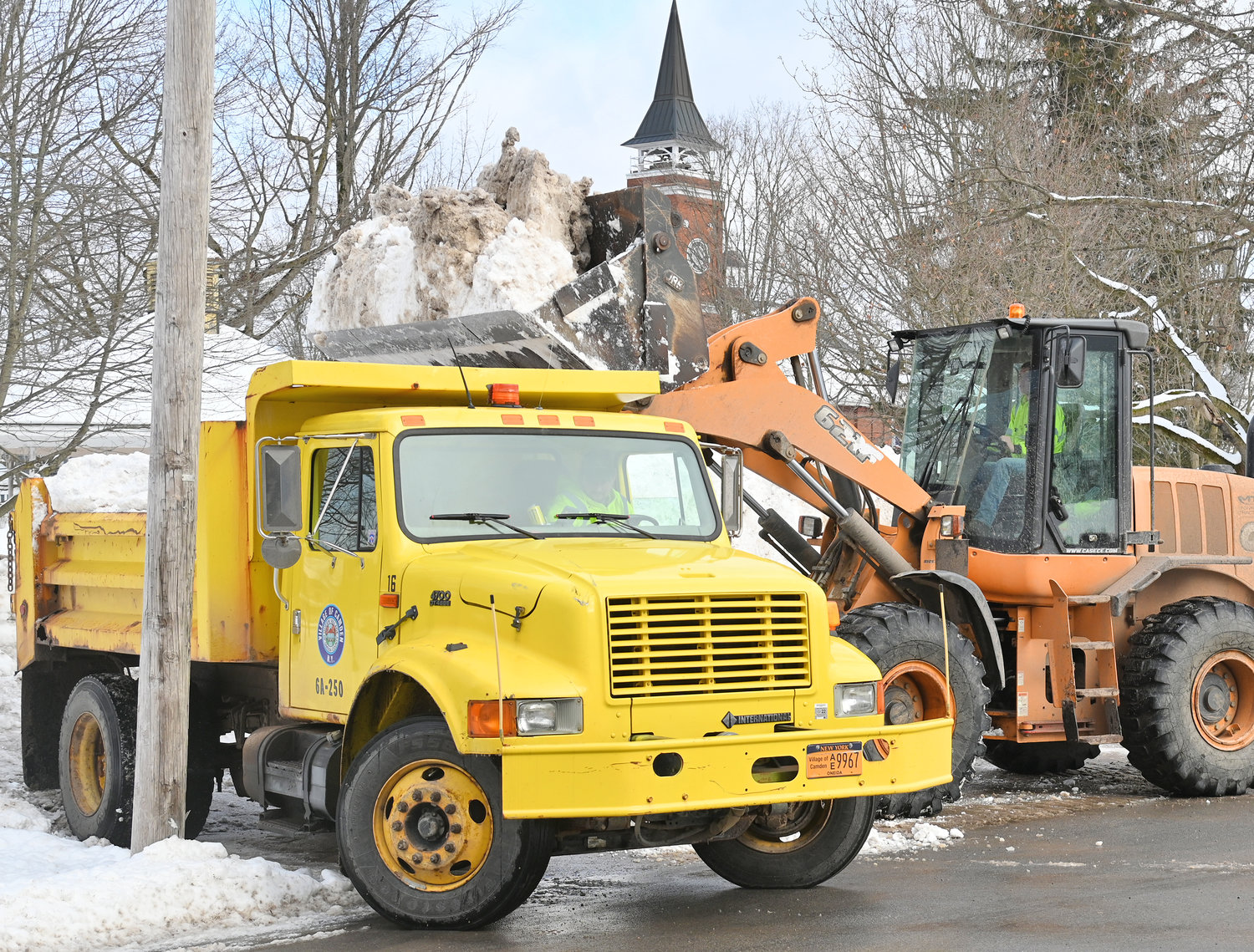 MAKING ROOM — Village of Camden employee Alex Gerrard uses a front loader to dump snow into the back of a dump truck driven by co-worker Jeremy Angel on Friday. The two were removing huge piles of snow in the village to make room for additional snow expected Sunday and Monday from Winter Storm Izzy.