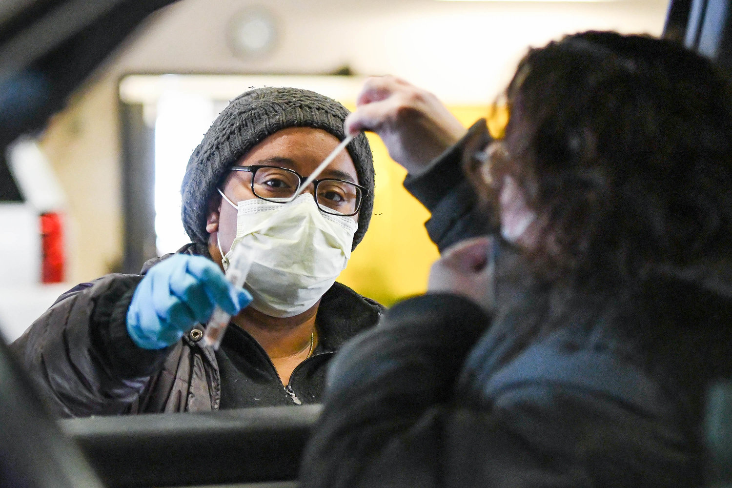 Noelle Feliz, left, holds out a test tube as a woman puts a nasal swab into it on Monday at Griffiss International  Airport. Precision Clinical Laboratories is offering drive-thru COVID-19 testing at Griffiss International Airport from 8:30 a.m. to 4:30 p.m. Monday through Friday.