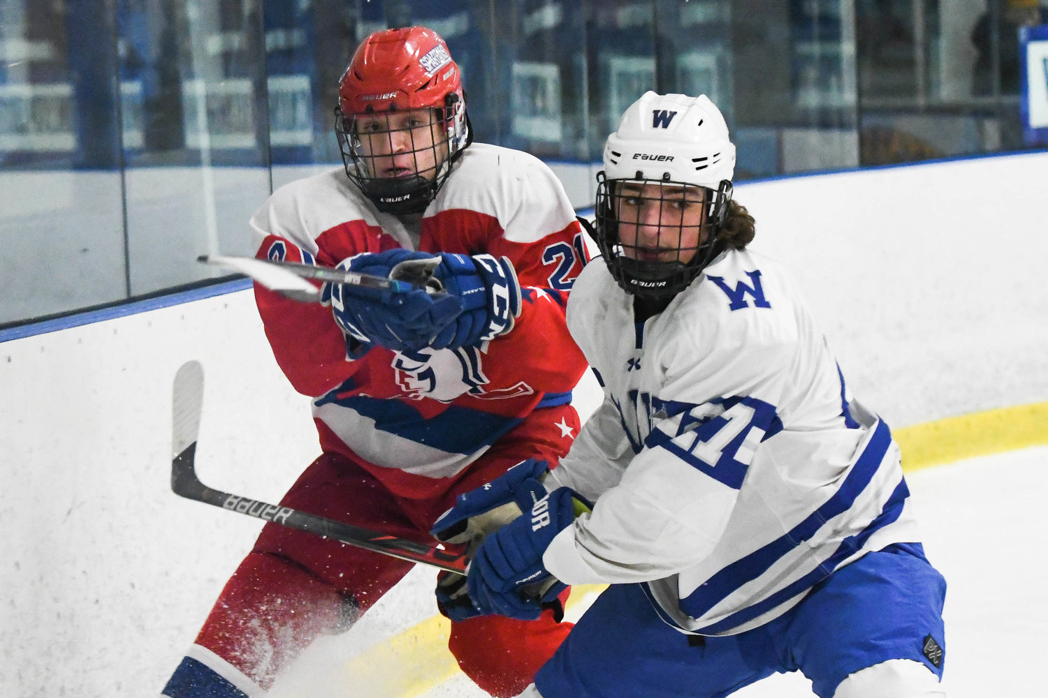 From left, New Hartford player Gabriel Syrotynski clears the puck away from Whitesboro player John Welch during the game on Tuesday, Feb. 8.