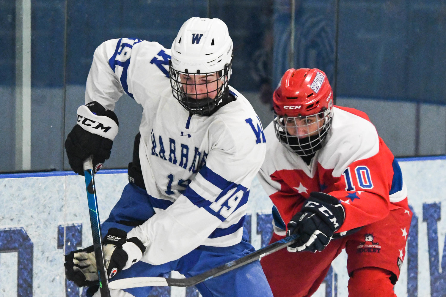 From left, Whitesboro player Kaeden Wood (19) moves the puck against New Hartford player Rowan Gall (10) during the game on Tuesday, Feb. 8.