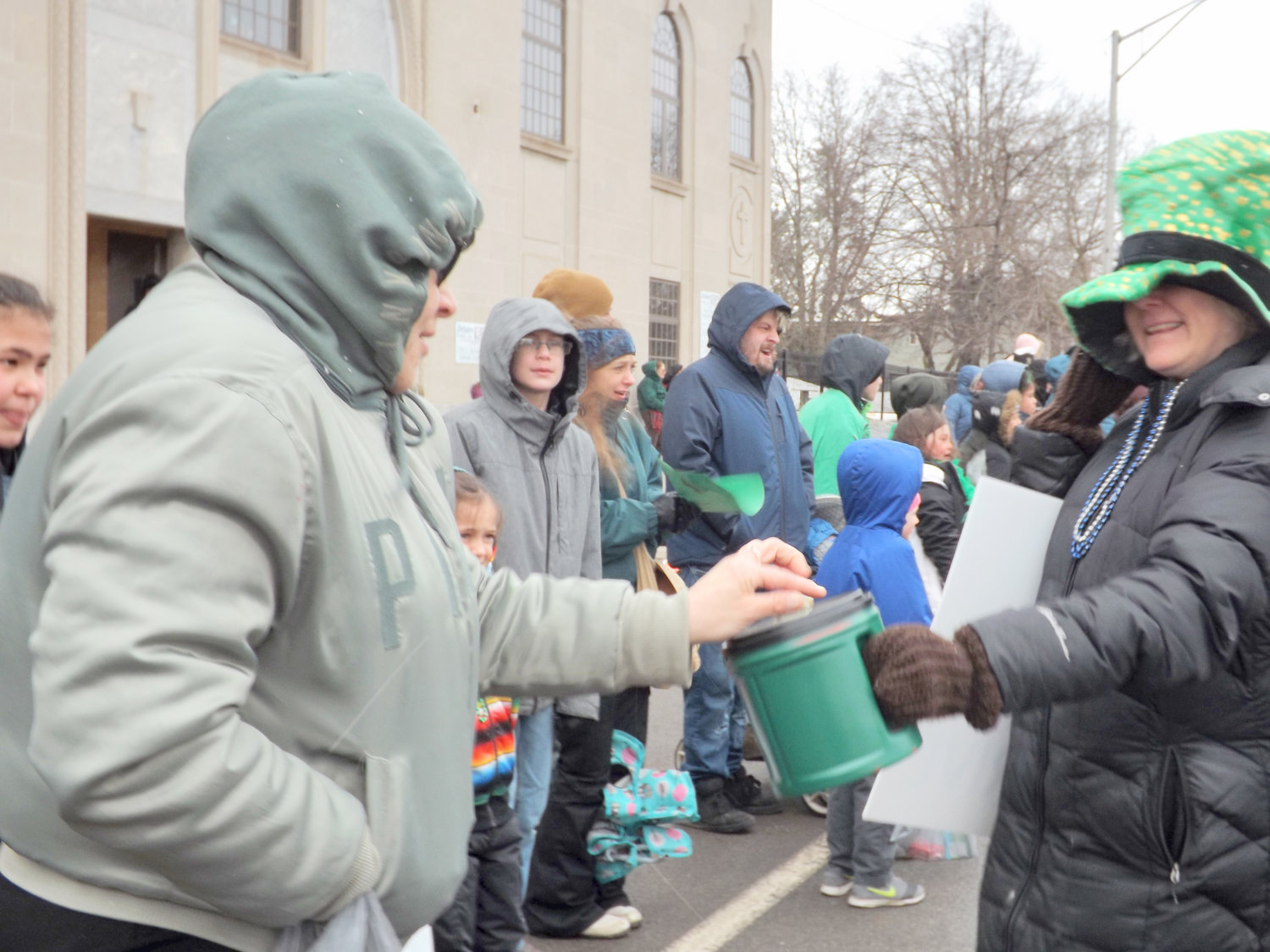 SHARING THE GREEN — A parade-goer at a past St. Patrick’s Day Parade in Utica donates cash to help feed those in need in the community. The annual food drive helps provide vital support for the Mother Marianne West Side Kitchen, organizer’s say.