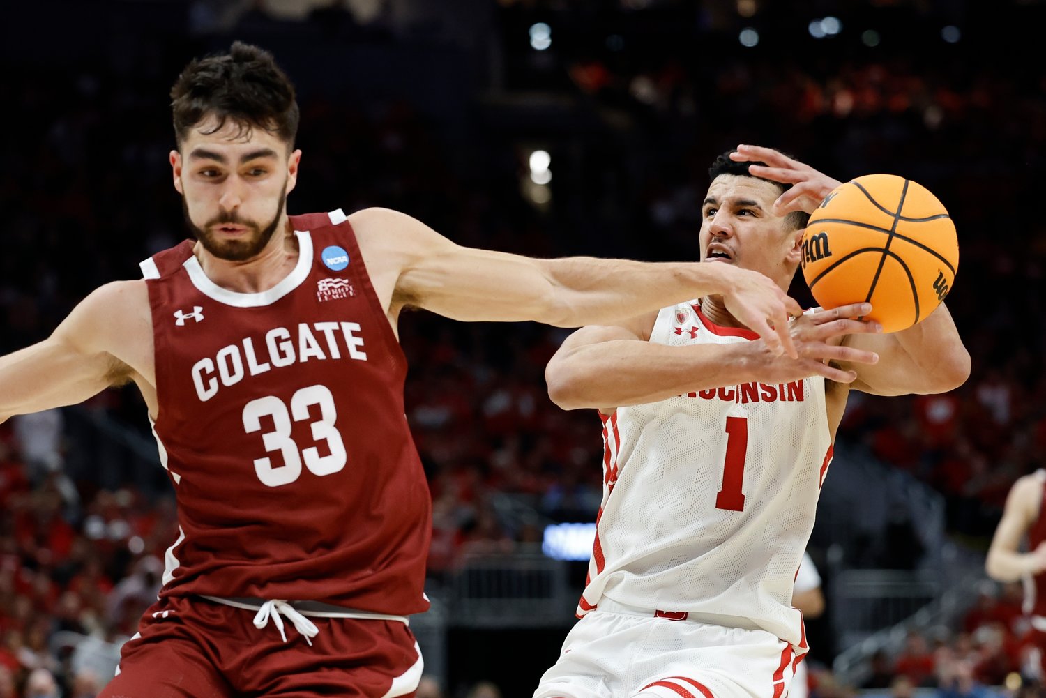 UP FOR GRABS — Wisconsin's Johnny Davis and Colgate's Oliver Lynch-Daniels go after a loose ball during the first half of a first-round NCAA men's basketball tournament game on Friday night in Milwaukee.
