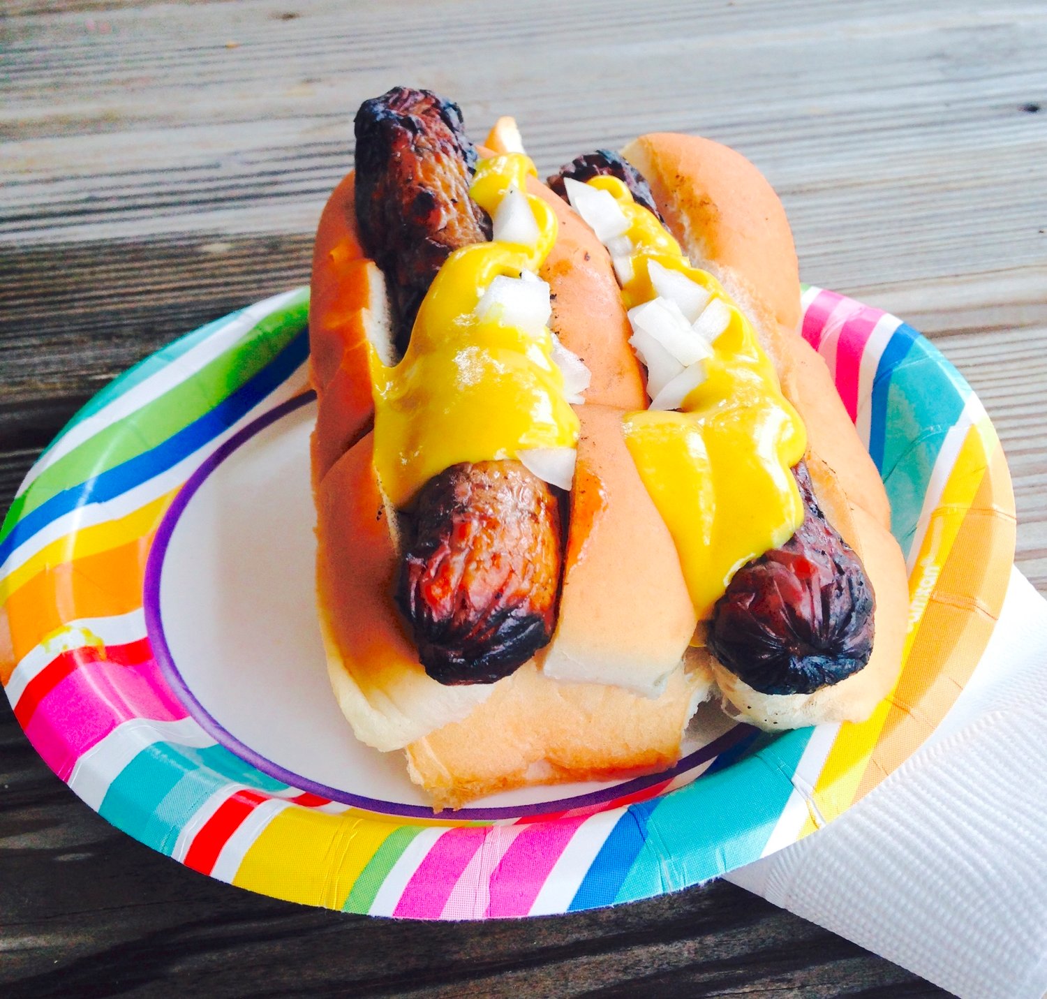 CLASSIC — Yellow mustard on top of a pair of grilled hotdogs.