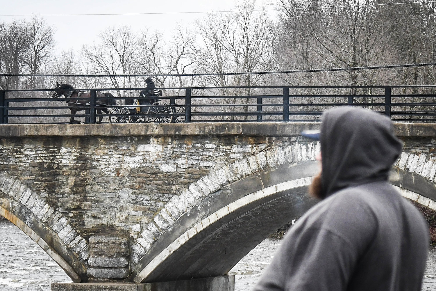 An amish buggy passes by as anglers go fishing near the Newport Stone Arch Bridge during opening day for trout season on Friday morning.