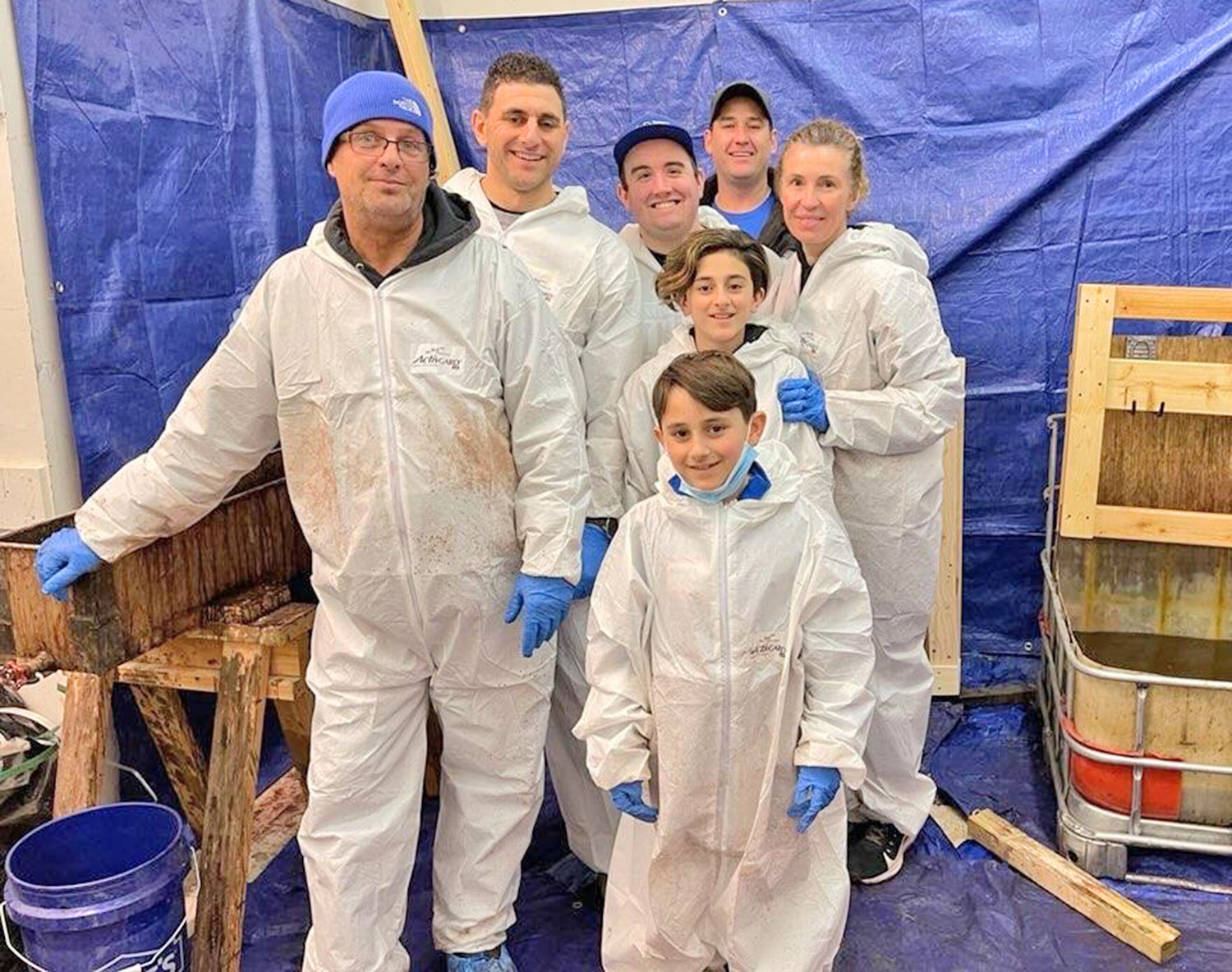 DIRTY WORK, BUT WORTH IT — Pictured are Tim Sheldon, Matt Nimey, Easton May, Matthew Nimey, Amelia Nimey, Richard Messineo and Beth Coombs at the staining tanks for Sleep in Heavenly Peace’s Mega Build on Sunday, April 3, at Sangertown Square in New Hartford.