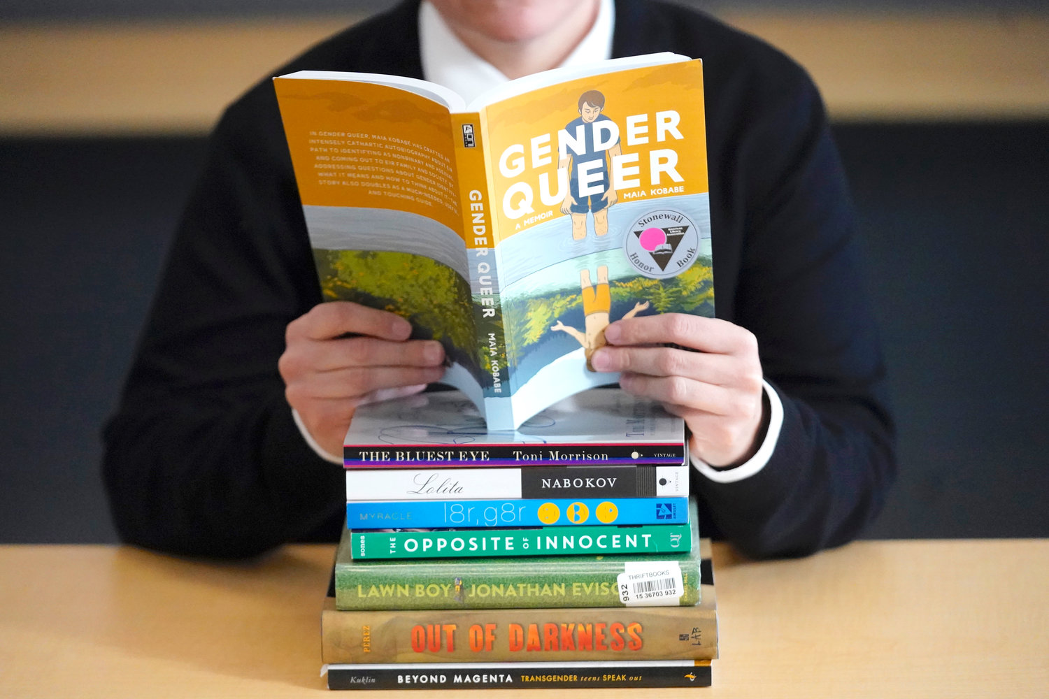 CHALLENGING — Amanda Darrow, director of youth, family and education programs at the Utah Pride Center, poses with books on Dec. 16, that have been the subject of complaints from parents in Salt Lake City.