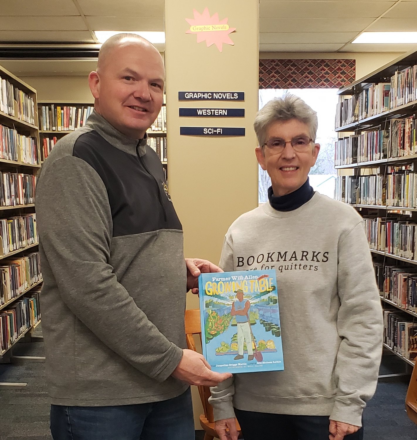 CELEBRATING AGRICULTURE — John Wagner of New York Farm Bureau, left, presents this year’s Agriculture Literacy Book of the year "Will Allen and the Growing Table" on behalf of the Oneida County Farm Bureau to Mary Kay Junglen, director of the Sherrill-Kenwood Free Library.