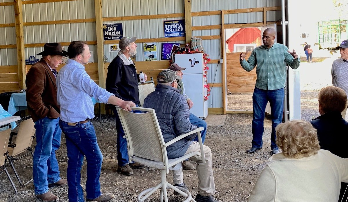 DOWN ON THE FARM — U.S. Congressman Antonio Delgado, D-19, right, addresses a group of farmers and local leaders at the dairy farm of Oneida County Sheriff Robert M. Maciol Friday afternoon.