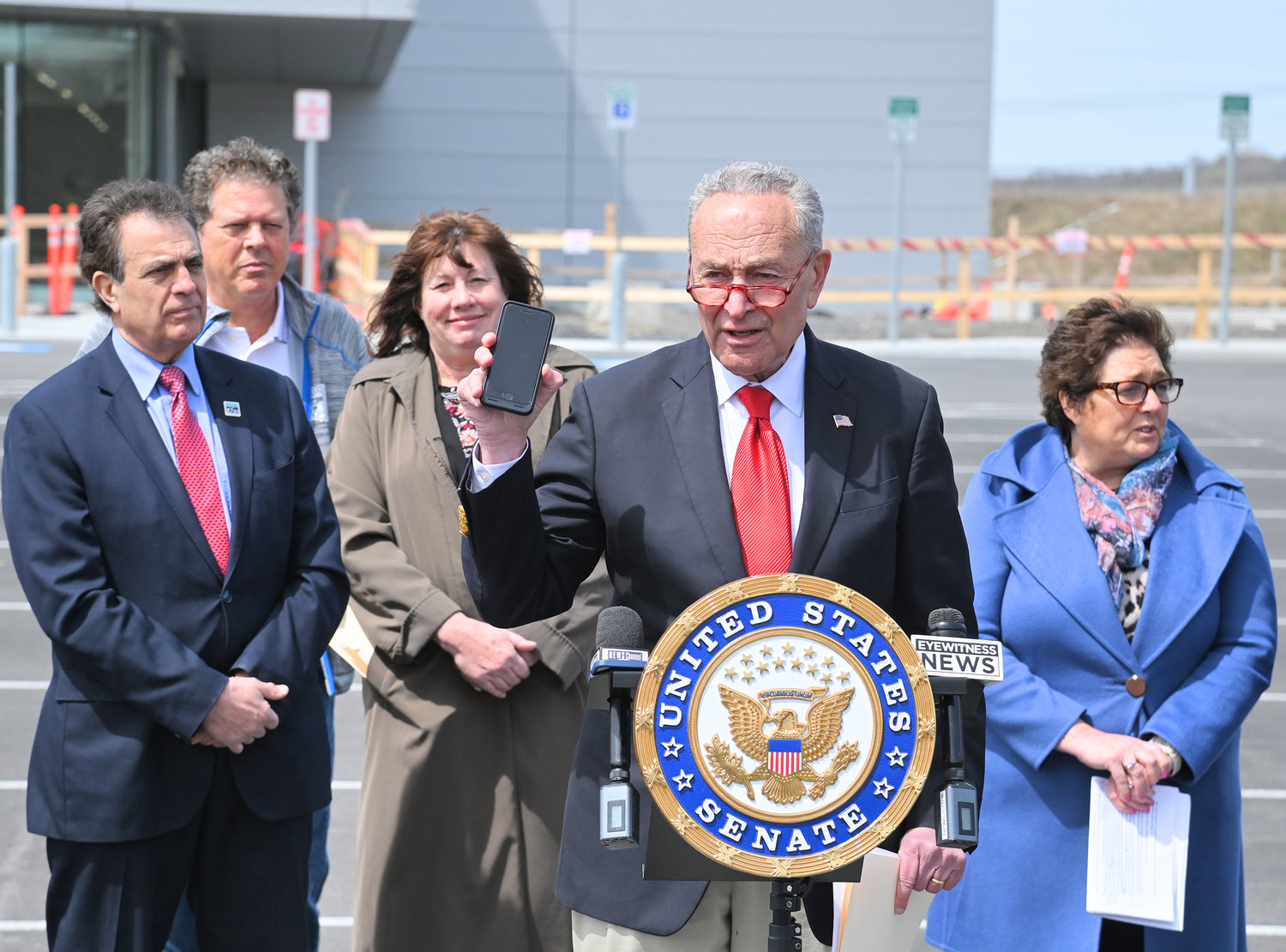 NEEDS CHIPS — U.S. Sen. Charles E. Schumer holds up a smartphone that uses the chips that will be produced at a chip fab facility like Wolfspeed during his press conference in Marcy on Monday.