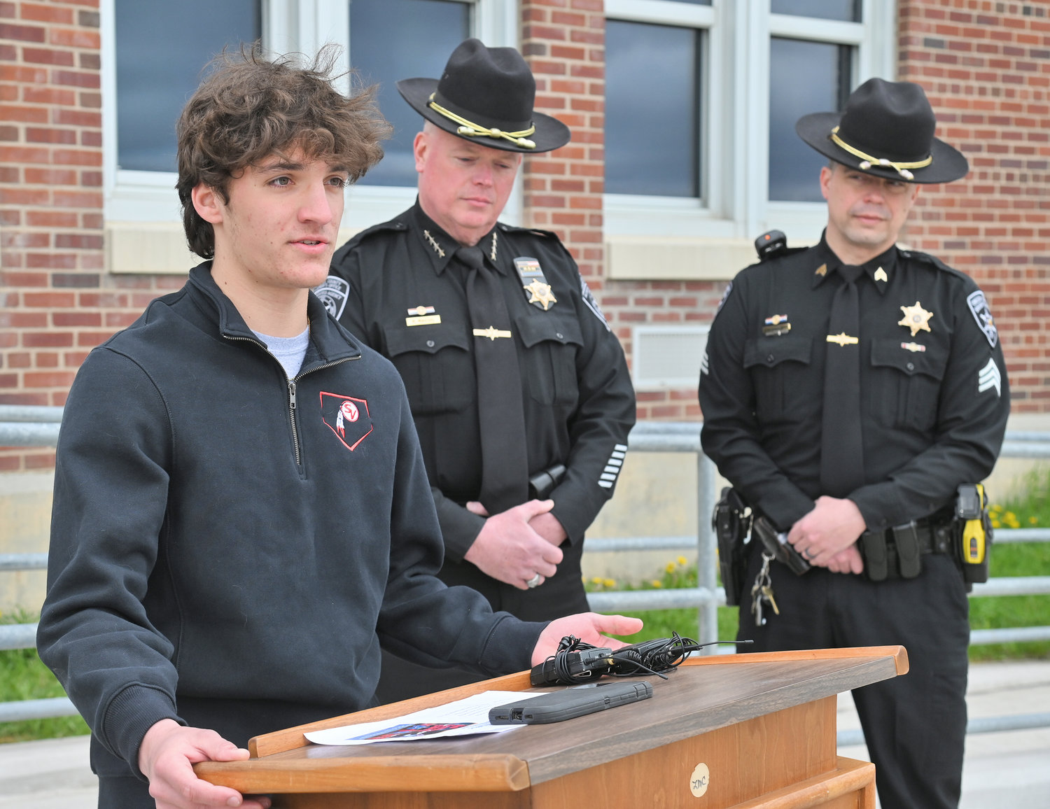 CLASS PRESIDENT SPEAKS — Sauquoit Valley High School senior class president Benjamin LoGalbo want his fellow students to stay safe as they approach prom and graduation season. He was joined outside his school Friday morning by Oneida County Sheriff Robert M. Maciol, center, and Sgt. Carey Phair.
